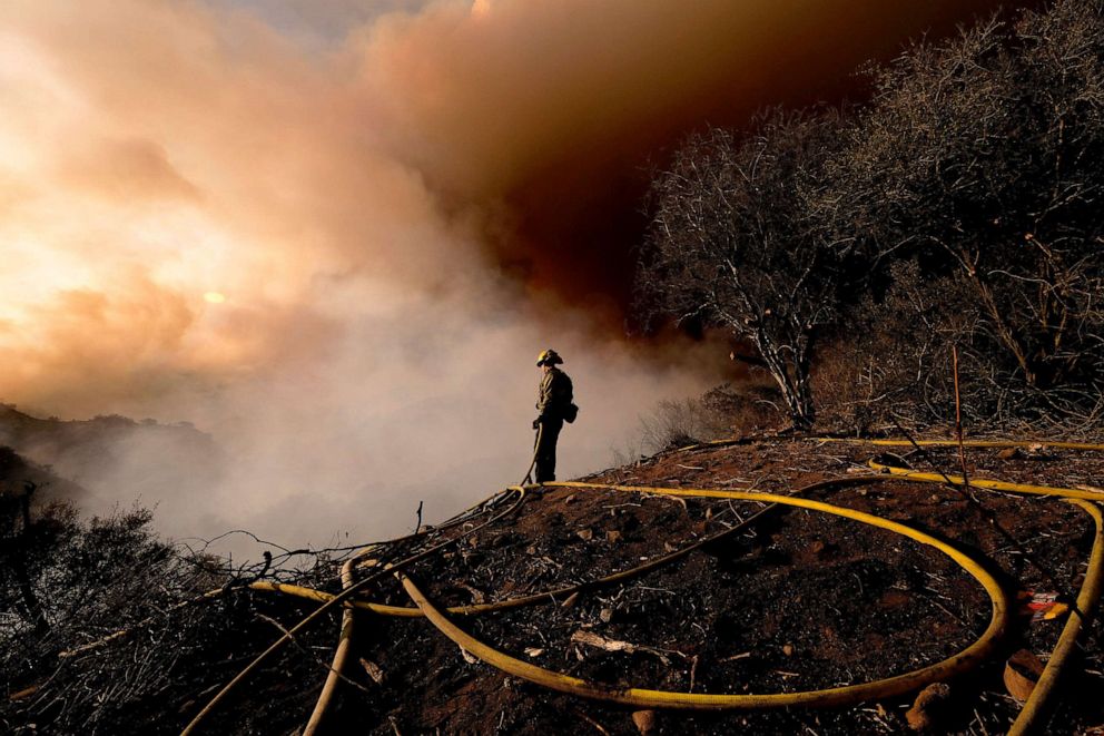 PHOTO: A firefighter keeps watch as smoke rises from a brush fire scorching at least 100 acres in the Pacific Palisades area of Los Angeles, May 15, 2021.