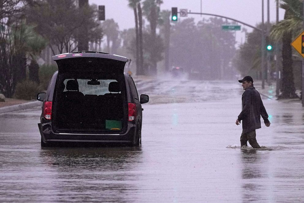 PHOTO: A motorist walks out to remove belongings from his vehicle after becoming stuck in a flooded street, Sunday, Aug. 20, 2023, in Palm Desert, Calif.