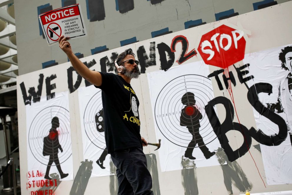 PHOTO: Manuel Oliver, father of Joaquin Oliver one of the victims of the mass shooting at Marjory Stoneman Douglas High School, holds up a placard as he paints a mural to commemorate the victims and promote gun control in Los Angeles, April 7, 2018.