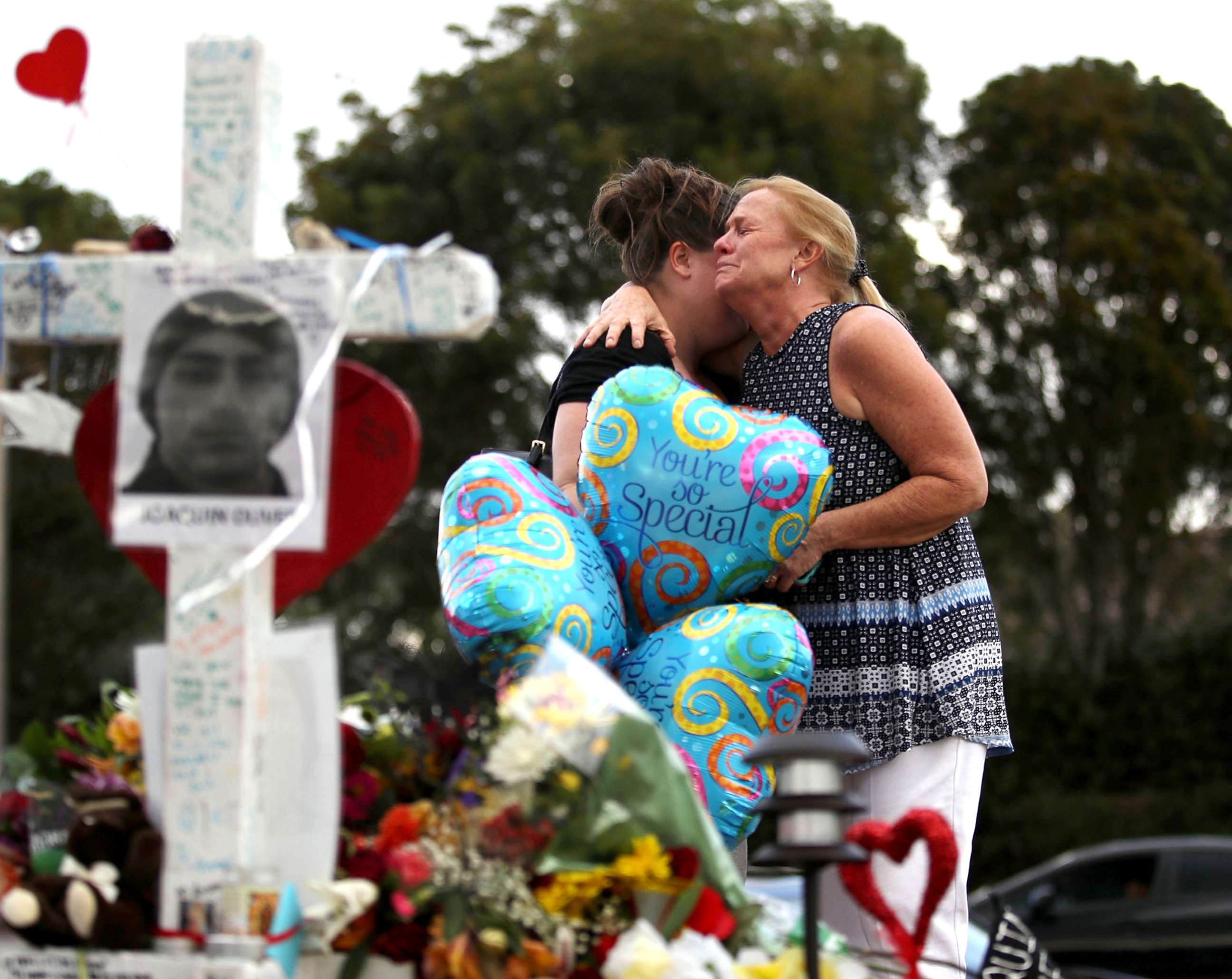 PHOTO: Cindy Sotelo (R) cries with her daughter, Jessica Malone, an alumna of Marjory Stoneman Douglas High School, as they visit a makeshift memorial setup in front of the school, Feb. 19, 2018 in Parkland, Fla. 