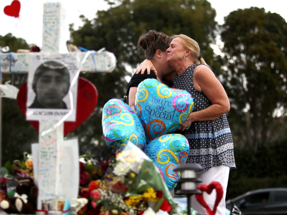 PHOTO: Cindy Sotelo (R) cries with her daughter, Jessica Malone, an alumna of Marjory Stoneman Douglas High School, as they visit a makeshift memorial setup in front of the school, Feb. 19, 2018 in Parkland, Fla. 