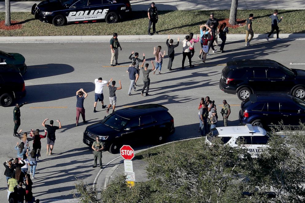 PHOTO: Students hold their hands in the air as they are evacuated by police from Marjory Stoneman Douglas High School in Parkland, Fla., Feb. 14, 2018, after a shooter opened fire on the campus. 