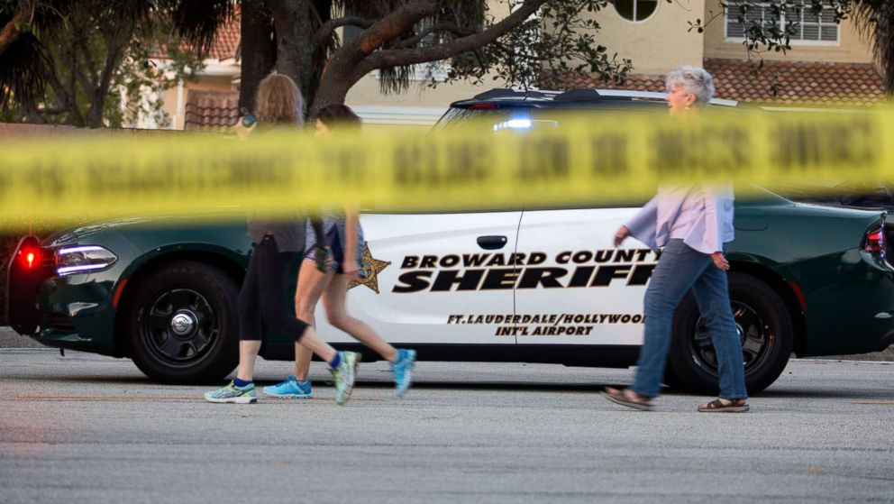 PHOTO: People walk in front of a Broward County sheriff car after a shooting at Marjory Stoneman Douglas High School in Parkland, Fla., Feb. 14, 2018.