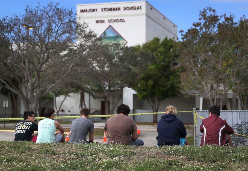 PHOTO: People look on at the Marjory Stoneman Douglas High School, Feb. 18, 2018 in Parkland, Fla.