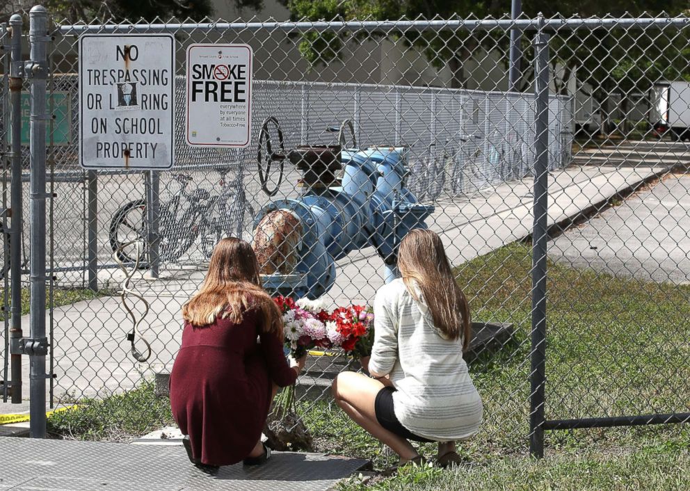 PHOTO: Students Jessica Garagro (L) and Sarah Goodchild, place flowers at a fence that surrounds Marjory Stoneman Douglas High School, Feb. 18, 2018 in Parkland, Fla.