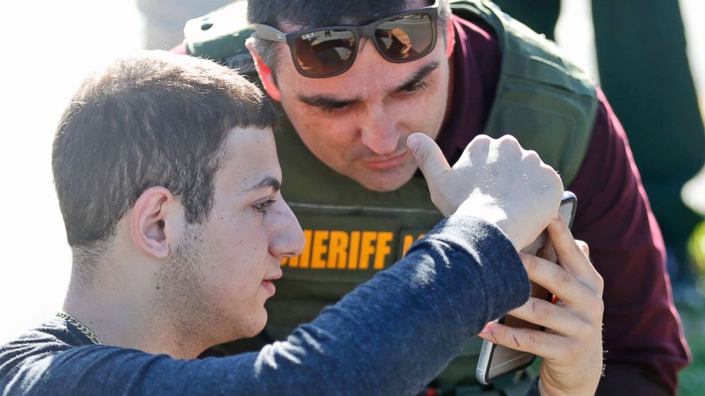 PHOTO: A student shows a law enforcement officer a photo or video from his phone after a shooting at Marjory Stoneman Douglas High School, Feb. 14, 2018, in Parkland, Fla.