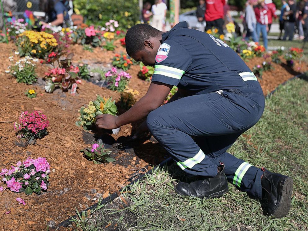 PHOTO: Devon Fuller places a plant in the ground at a garden setup in memory of those lost a year ago during a mass shooting at Marjory Stoneman Douglas High School, Feb. 14, 2019 in Parkland, Fla.