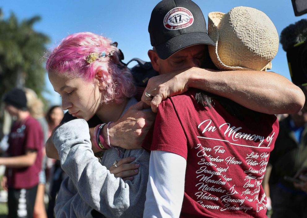 PHOTO: Anthony Gonzalez hugs his daughter, Victoria Gonzalez and her teacher Ronit Reoven, right, as they visit a memorial setup near Marjory Stoneman Douglas High School, Feb. 14, 2019 in Parkland,  Fla.