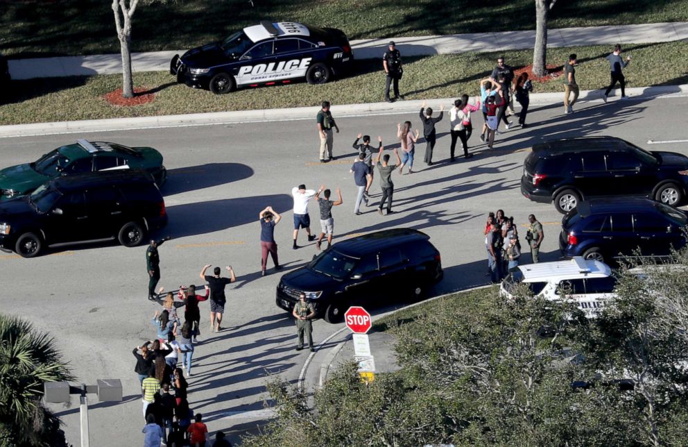 PHOTO: Students hold their hands in the air as they are evacuated by police from Marjory Stoneman Douglas High School in Parkland, Fla., after a shooter opened fire on the campus, Feb.14, 2018.