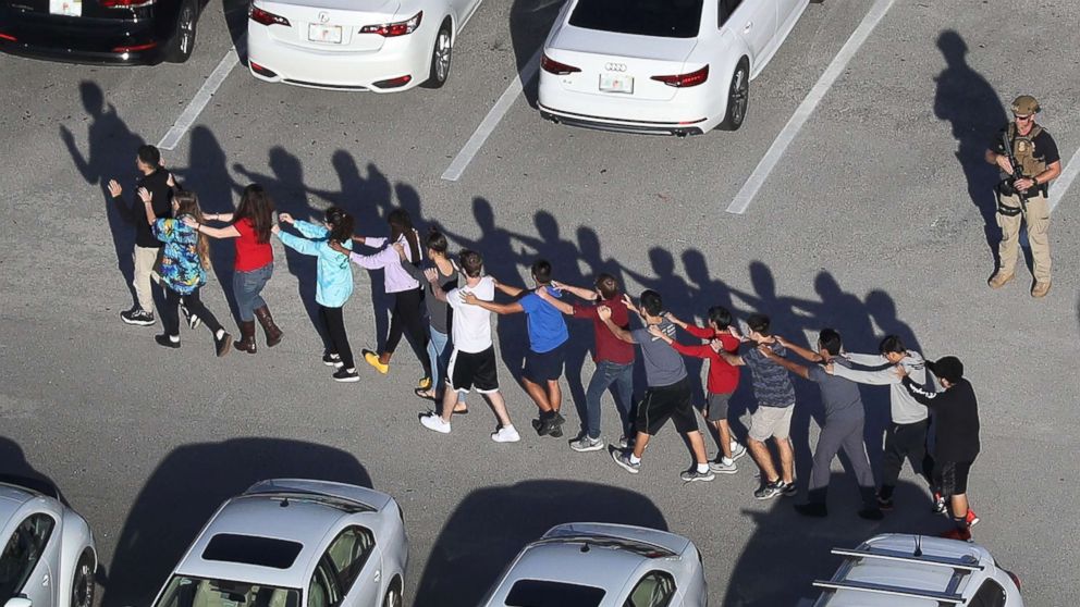 People are brought out of the Marjory Stoneman Douglas High School after a shooting at the school, Feb. 14, 2018, in Parkland, Fla.
