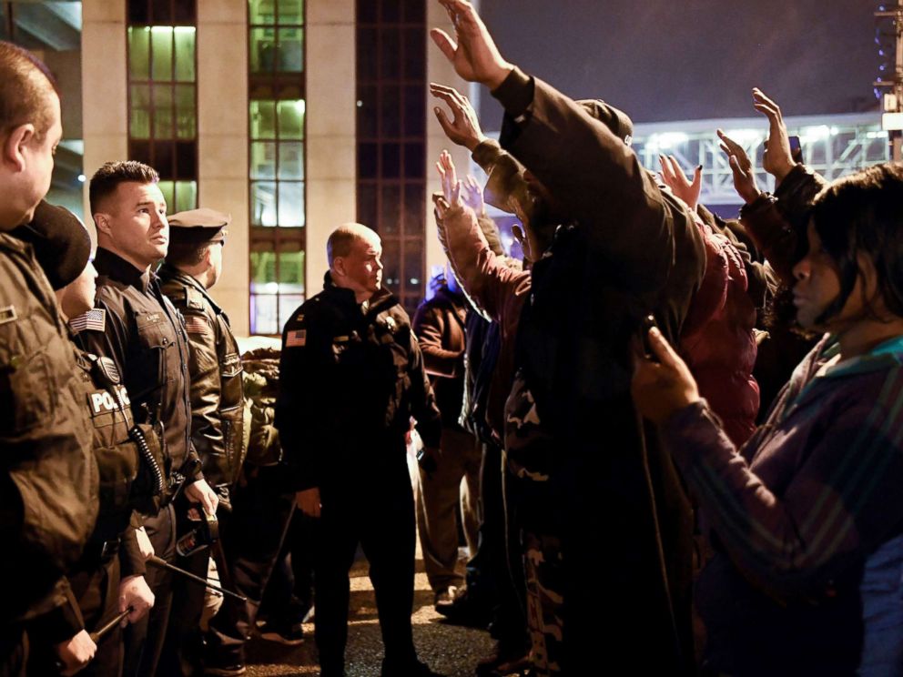 PHOTO: Protesters raise their hands as they face police officers during a rally in reaction to the death of Jameek Lowery, Jan. 8, 2019, in Paterson, N.J. Lowery died after asking the Paterson Police Department for help.