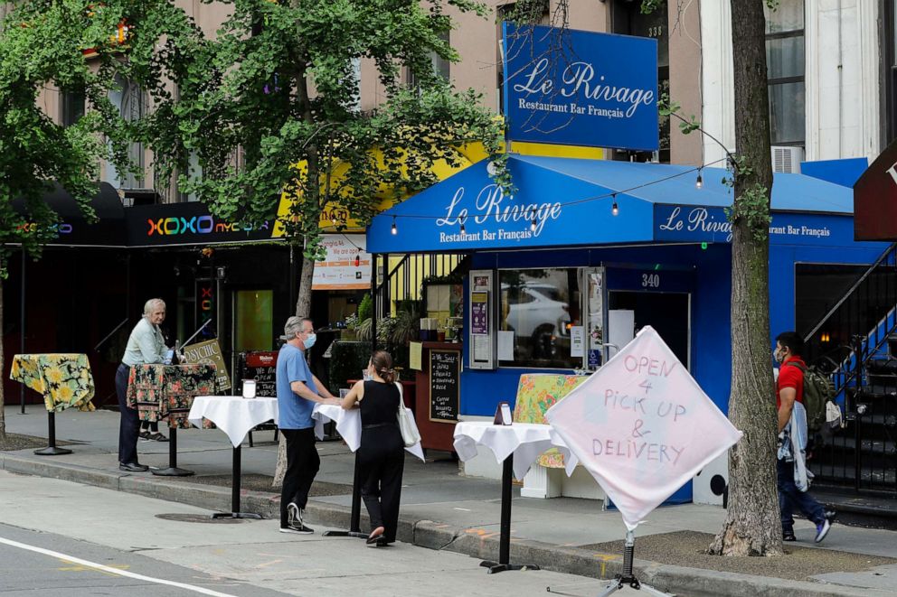 PHOTO: Patrons wear protective face masks during the coronavirus pandemic while standing at tables placed outside of restaurants in New York City on May 28, 2020.