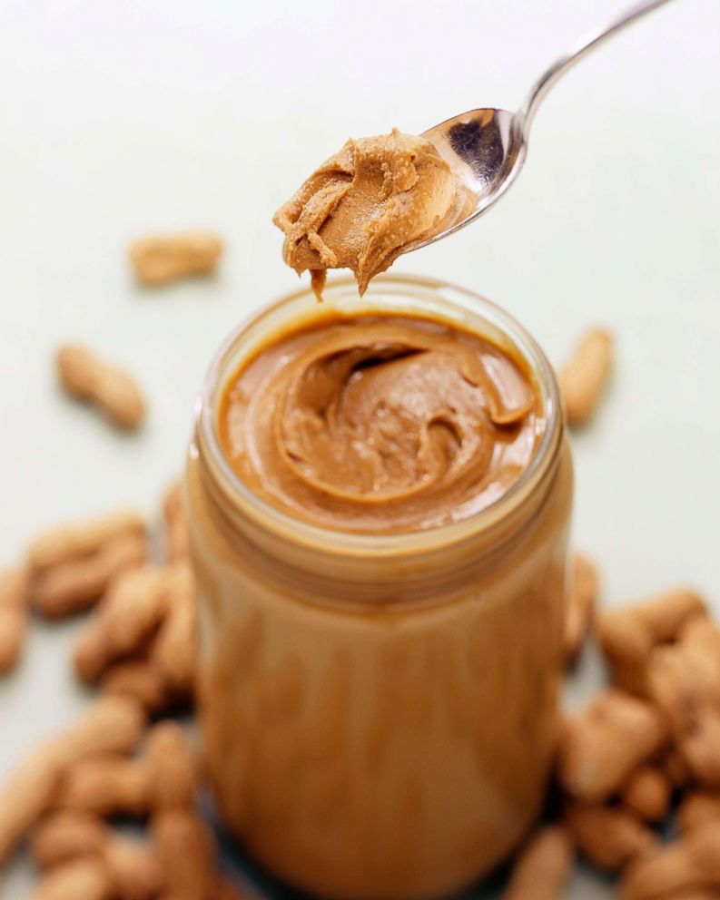 PHOTO: A jar of natural peanut butter is pictured with peanuts in the background and a spoon full of peanut butter in this undated stock photo.