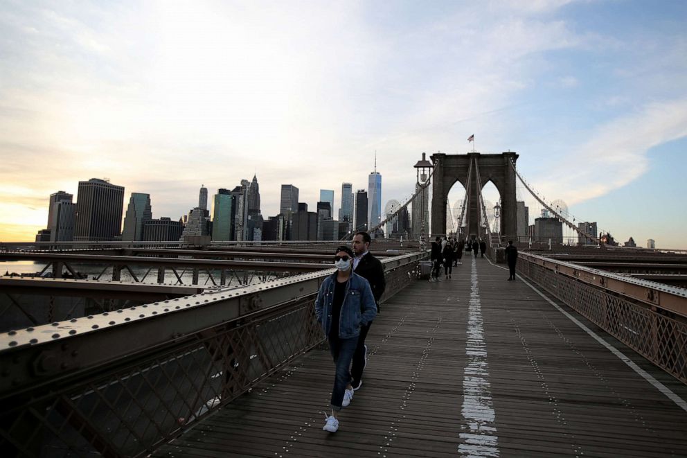 PHOTO: A pedestrian, wearing a protective face mask walks the Brooklyn Bridge in the Dumbo neighborhood of the Brooklyn borough of New York City on March 24, 2020.