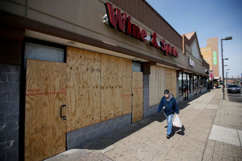 PHOTO: In this March 18, 2020, file photo, a pedestrian walks past a boarded up Wine and Spirits store in Upper Darby, Penn.