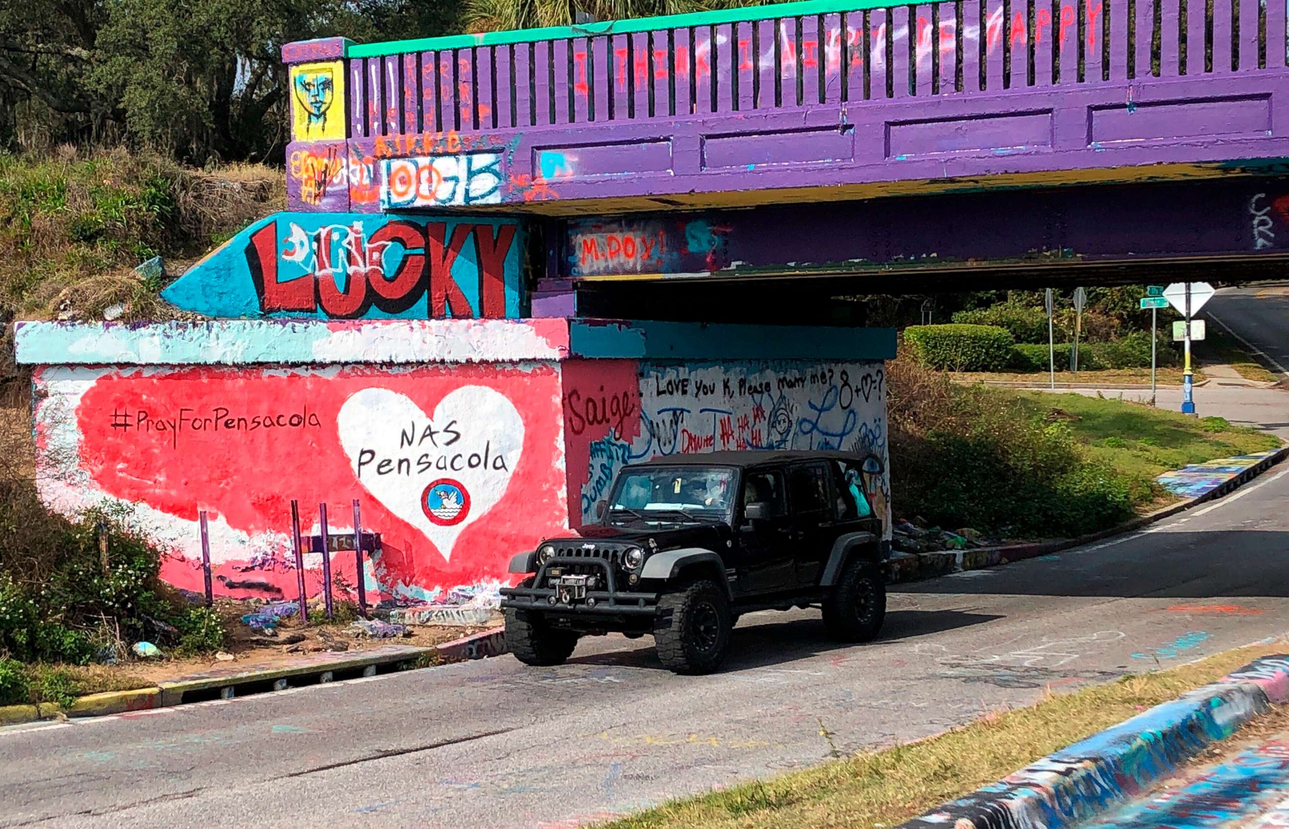 PHOTO: A vehicle drives by a tribute to victims of the Naval Air Station Pensacola that was freshly painted on what is known as Graffiti Bridge in downtown Pensacola, Fla., on Saturday, Dec. 7, 2019.