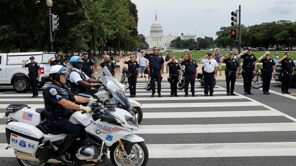 PHOTO: Members of law enforcement agencies in Washington salute as a ceremonial procession in honor of the police officer wounded in a shooting at the Pentagon earlier in the day drives past the U.S. Capitol in Washington, Aug. 3, 2021.