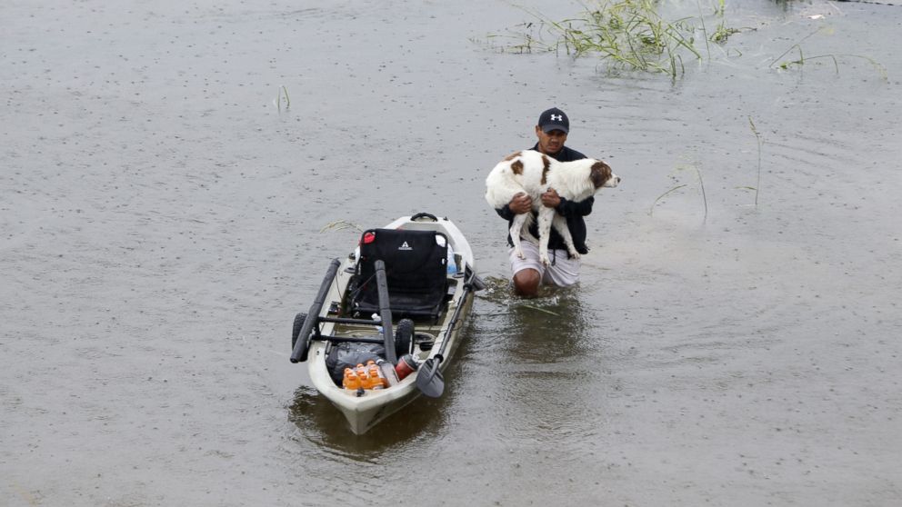 PHOTO: A man holding his dog walks in water in greater Houston area of Texas, Aug. 27, 2017. 