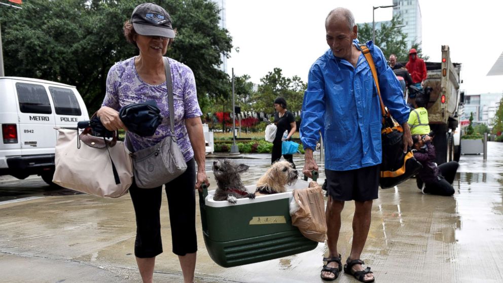 PHOTO: A couple of evacuees carry their dogs into the the George R. Brown Convention Center after Hurricane Harvey inundated the Texas Gulf coast with rain causing widespread flooding, in Houston, Aug. 27, 2017. 
