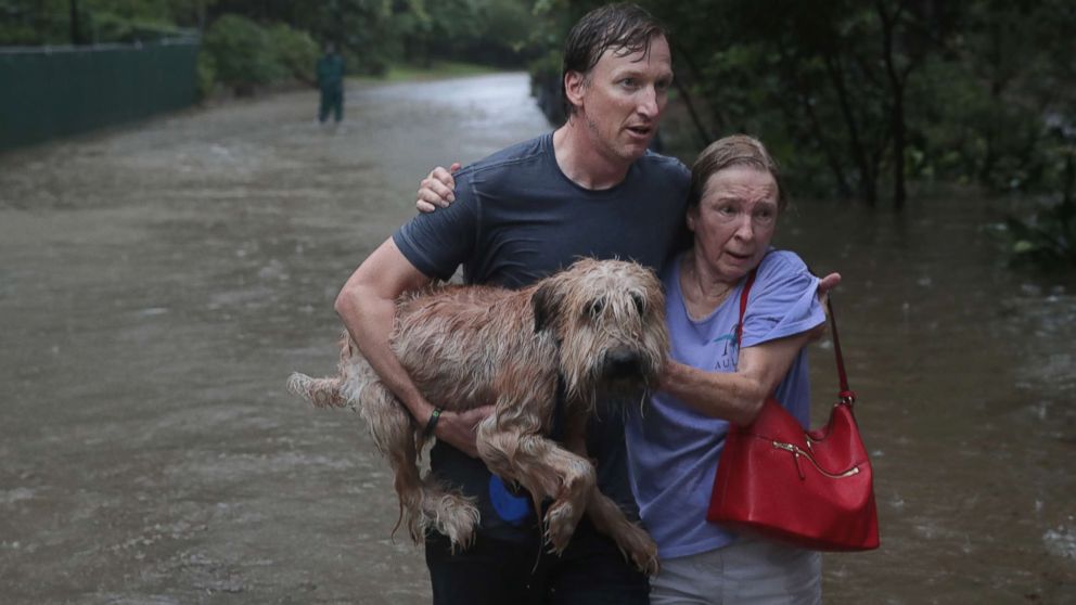 PHOTO: Andrew White (L) helps a neighbor down a street after rescuing her from her home in his boat in the upscale River Oaks neighborhood after it was inundated with flooding from Hurricane Harvey, Aug. 27, 2017, in Houston.