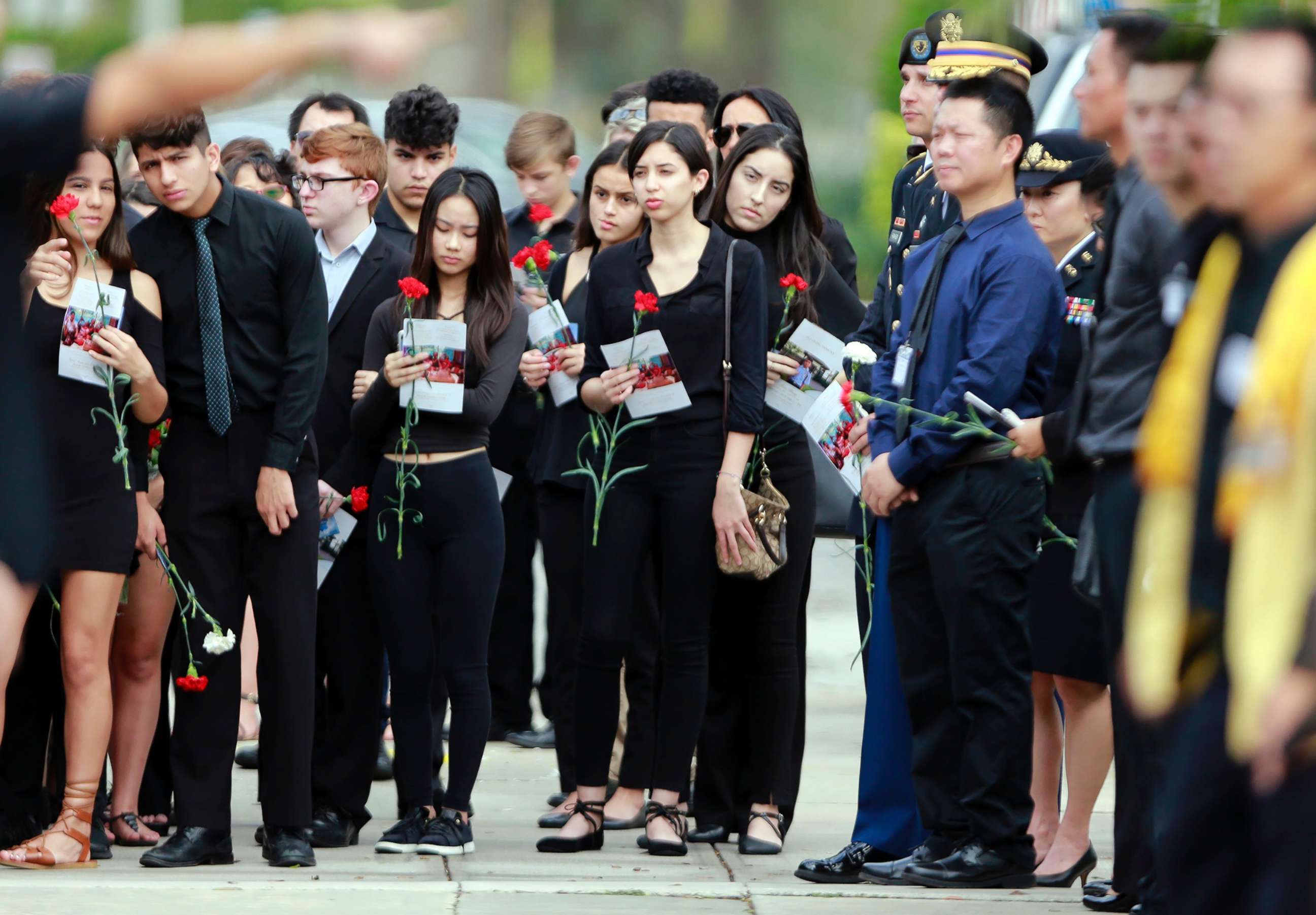 PHOTO: Mourners hold flowers during the funeral for Peter Wang at Kraeer Funeral Home in Parkland, Fla., on Feb. 20, 2018.