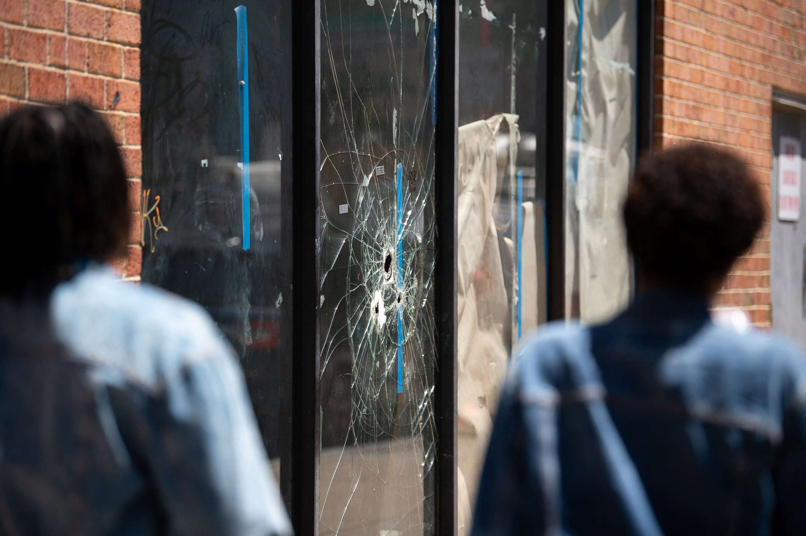 PHOTO: Pedestrians walk past bullet holes in the window of a store front on South Street in Philadelphia, June 5, 2022.
