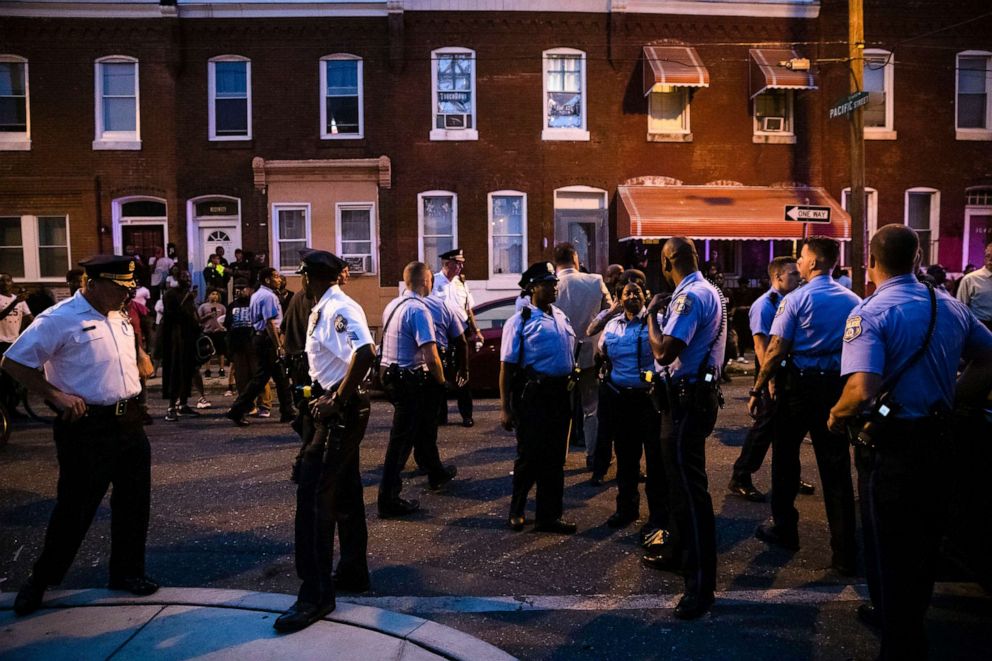 PHOTO: Officers gather for crowd control near a massive police presence set up outside a house as they investigate an active shooting situation, in Philadelphia, Aug. 14, 2019.