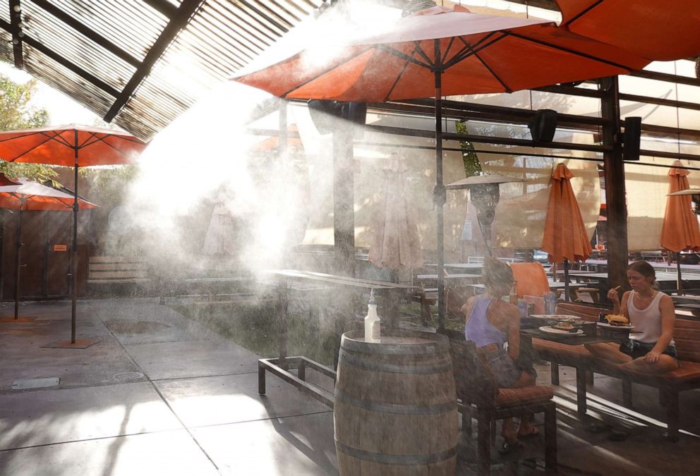 PHOTO: People eat beneath water misters at a restaurant on July 21, 2022 in Phoenix.