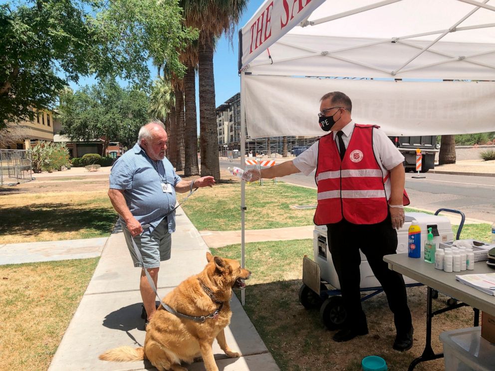 PHOTO: Salvation Army Maj. David Yardley offers water to a passerby at a heat relief station offering cold water and a cool place to rest out of the heat in Phoenix, May 28, 2020.