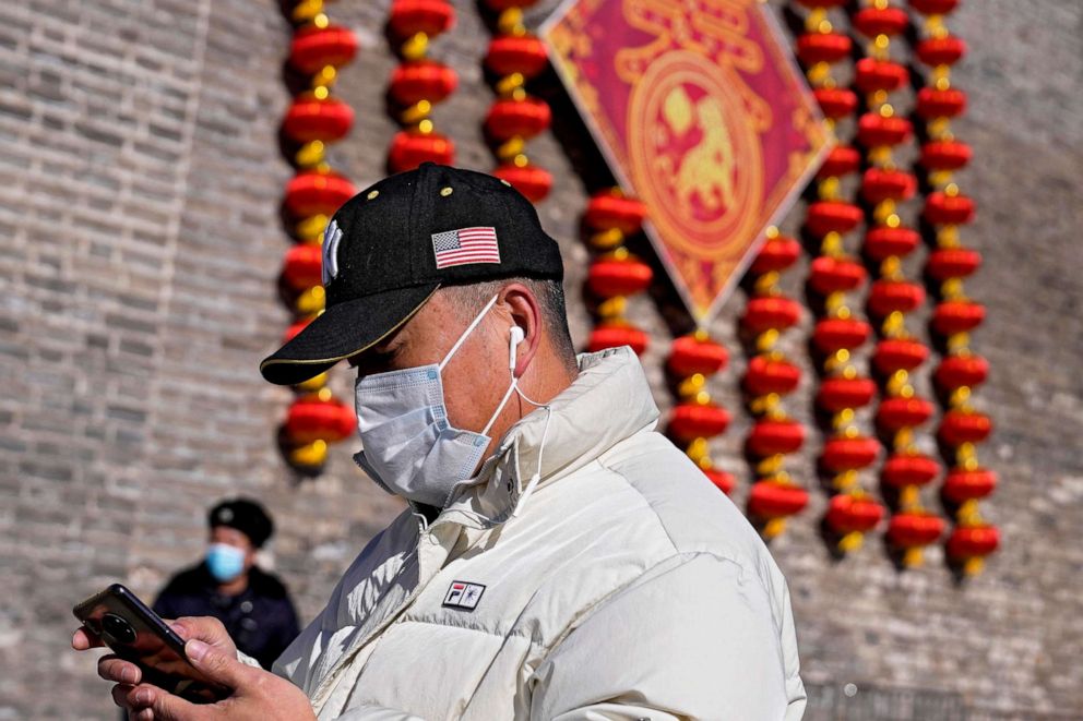 PHOTO: A man uses his phone while walking near a wall decorated with lanterns in Beijing, Jan. 27, 2022.
