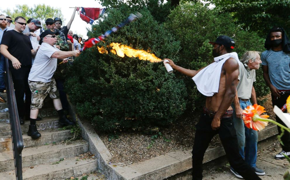 PHOTO: A counter demonstrator uses a lighted spray can against a white nationalist demonstrator at the entrance to Lee Park in Charlottesville, Va., Aug. 12, 2017.