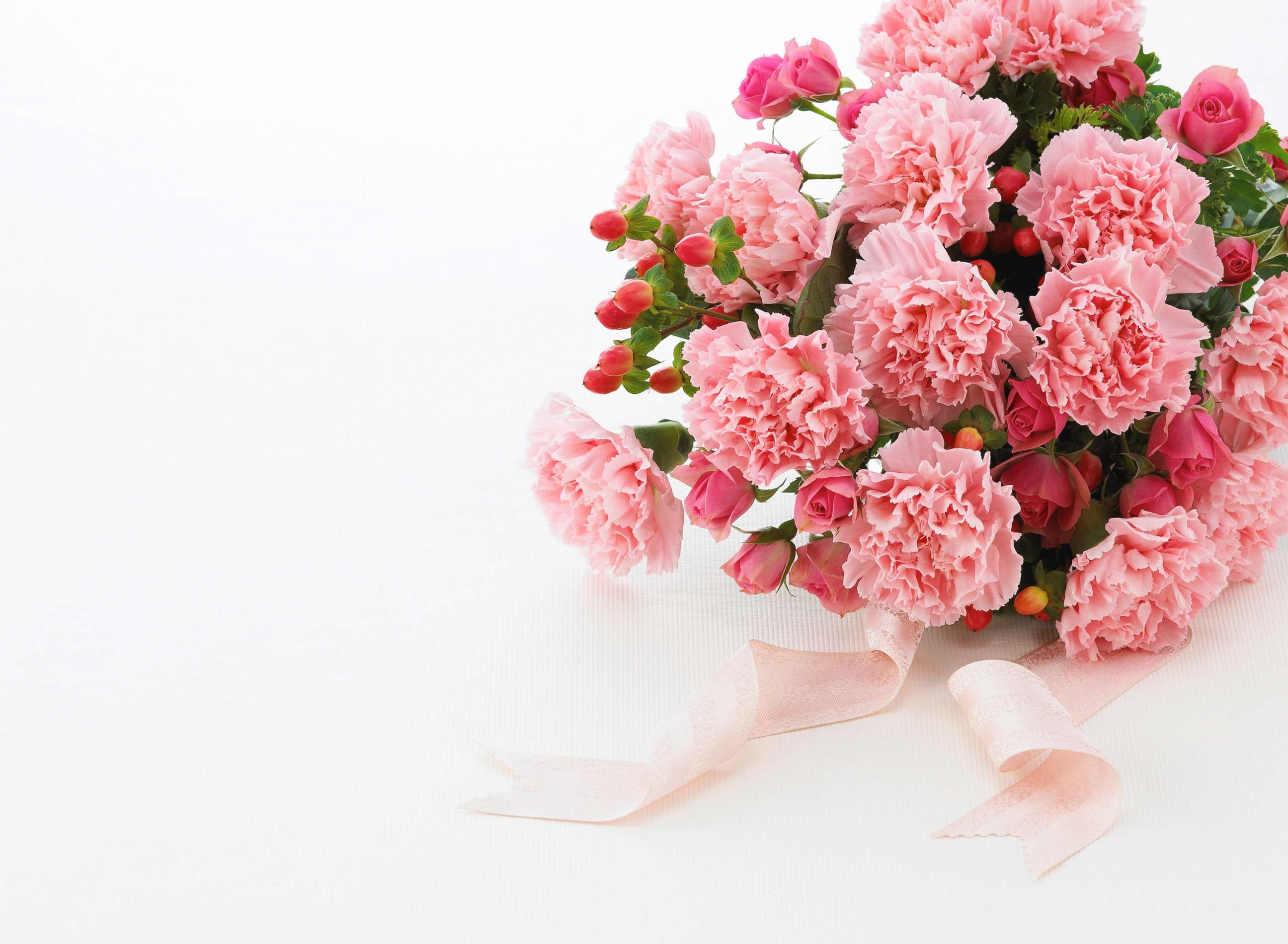 PHOTO: Bouquet of pink carnations sits on the table with a pink ribbon. 
