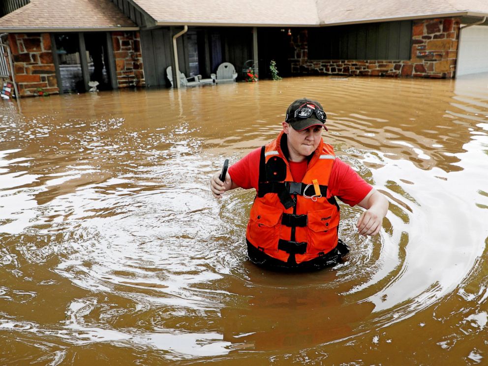 PHOTO: Tulsa County Sheriffs Deputy Miranda Munson makes her way back to a fan boat after checking a flooded house for occupants in the Town and Country neighborhood in Sand Springs, Okla., Thursday, May 23, 2019.