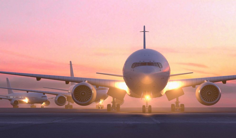 PHOTO: Airplanes taxiing on runway at sunset.