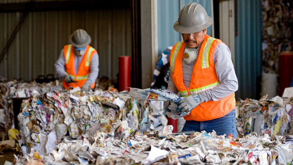 PHOTO: Workers remove plastic from piles of paper, plastic, metal and green waste at a recycling plant in Huntington Beach, Calif.