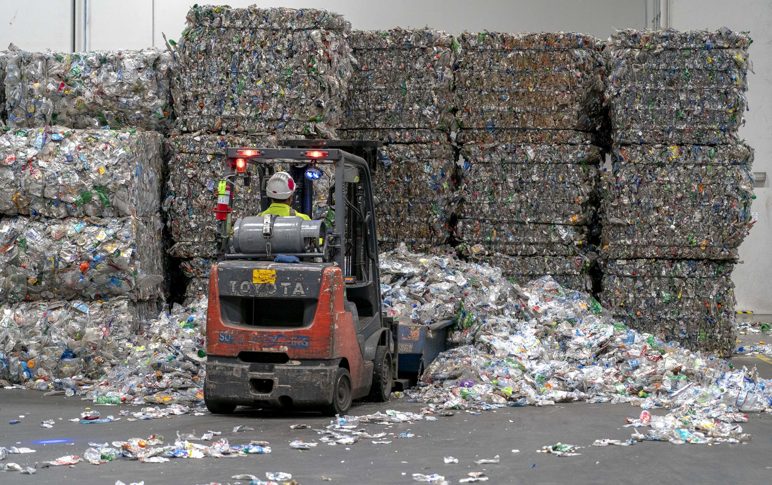 PHOTO: In this June 22, 2022, file photo, an employee operates a forklift to move bales of plastic bottles at the rPlanet Earth plastics recycling plant in Vernon, Calif.