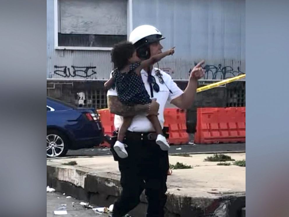 PHOTO: Sgt. Ed Pisarek, of The Philadelphia Highway Patrolm helping escort a baby from one of the daycare center during the shootout.