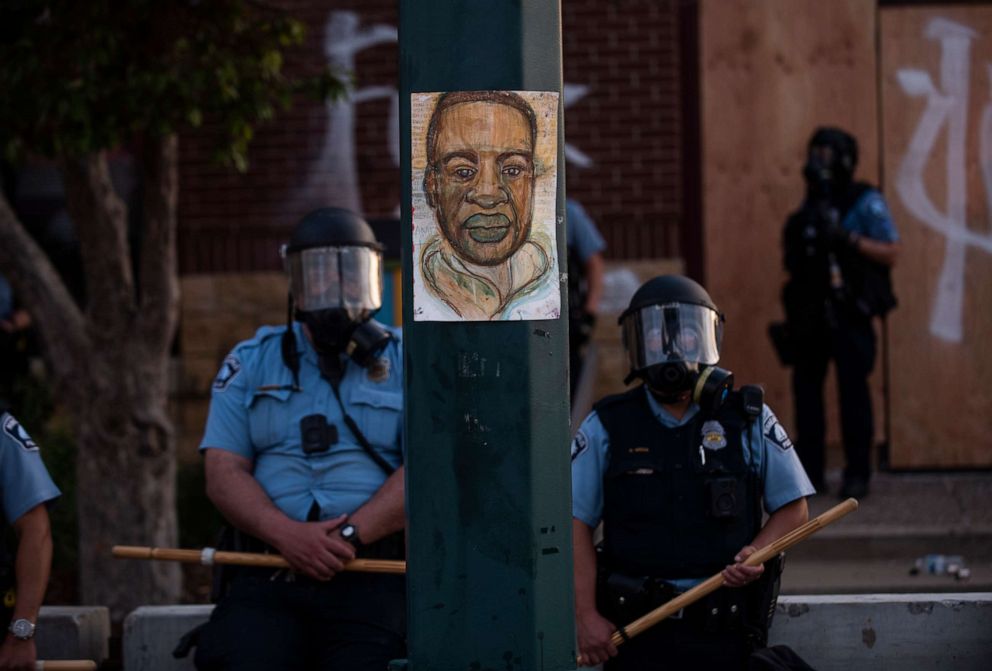 PHOTO: A portrait of George Floyd hangs on a street light pole as police officers stand guard at the Third Police Precinct during a face off with a group of protesters on May 27, 2020, in Minneapolis.