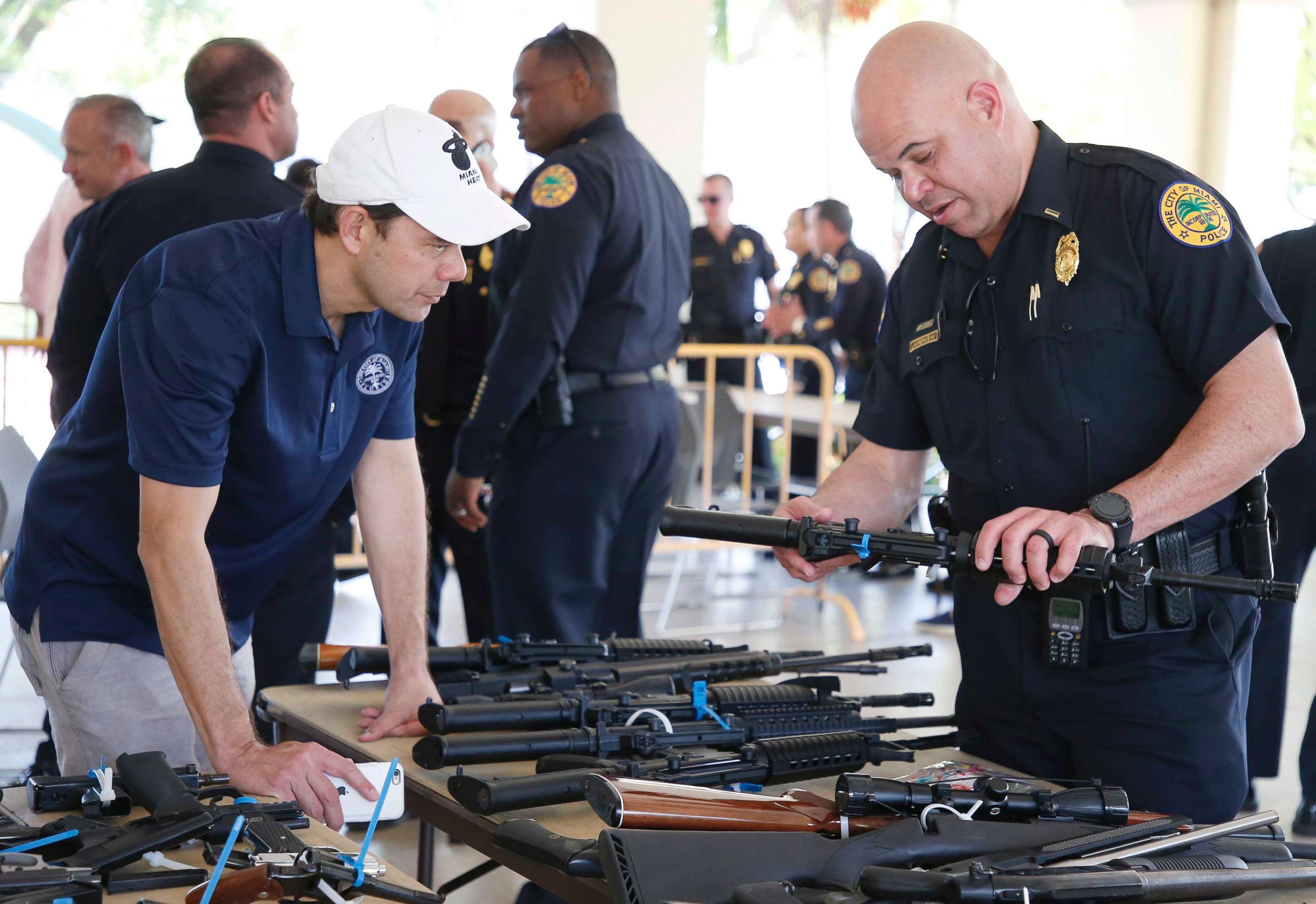 PHOTO: City of Miami Commissioner Ken Russell and City of Miami Police Officer Laurenceau look at some of the returned guns during a City of Miami gun buy-back event in Miami, March 17, 2018.