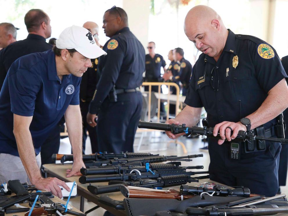 PHOTO: City of Miami Commissioner Ken Russell and City of Miami Police Officer Laurenceau look at some of the returned guns during a City of Miami gun buy-back event in Miami, March 17, 2018.