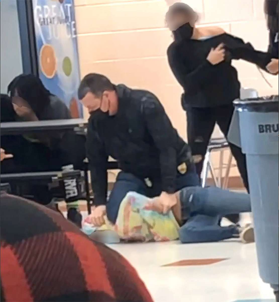 PHOTO: An off-duty police officer responds to a fight between two students at Lincoln Middle School in Kenosha, Wis., on March 4, 2022, in a still image from video. The officer appeared to kneel on the neck of a student, prompting an investigation.