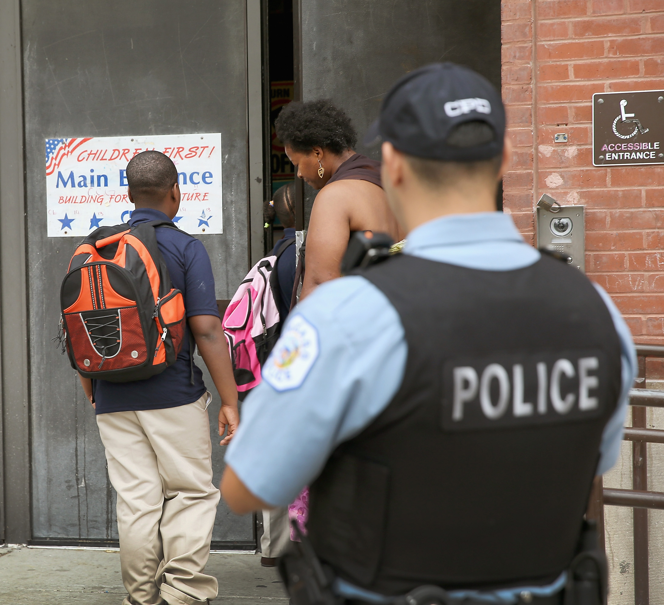 PHOTO: A probationary Chicago Police officer watches as students arrive at Laura Ward Elementary School on the Westside on Aug. 28, 2013 in Chicago.