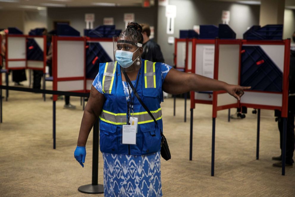 PHOTO: A poll worker wearing personal protective equipment directs voters to cast their ballots for the upcoming presidential election as early voting begins in Cincinnati, Ohio, on Oct. 6, 2020.