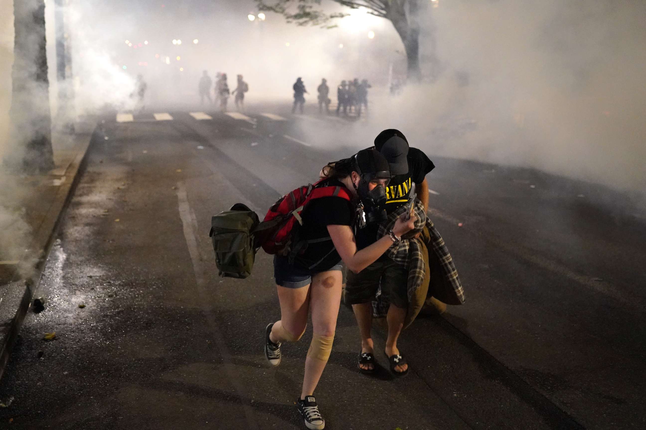 PHOTO: Two protesters flee through tear gas after federal officers dispersed a crowd of about a thousand at the Mark O. Hatfield U.S. Courthouse on July 21, 2020 in Portland, Ore.