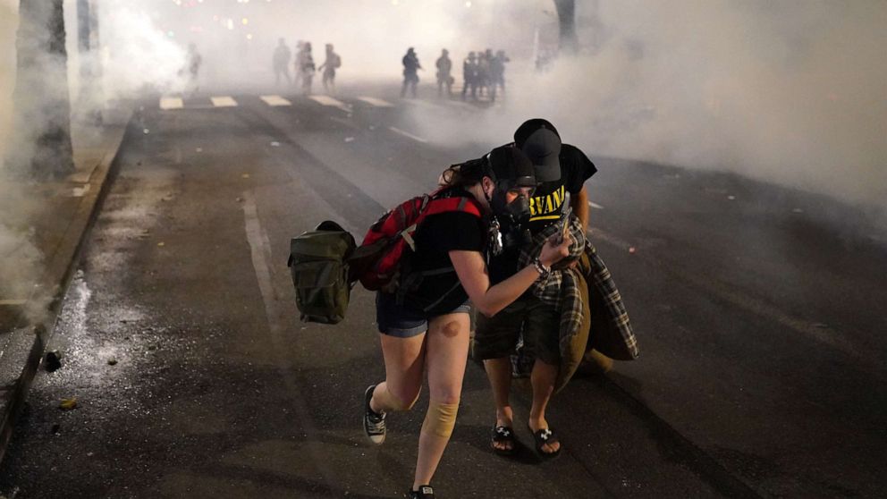 PHOTO: Two protesters flee through tear gas after federal officers dispersed a crowd of about a thousand at the Mark O. Hatfield U.S. Courthouse on July 21, 2020 in Portland, Ore.