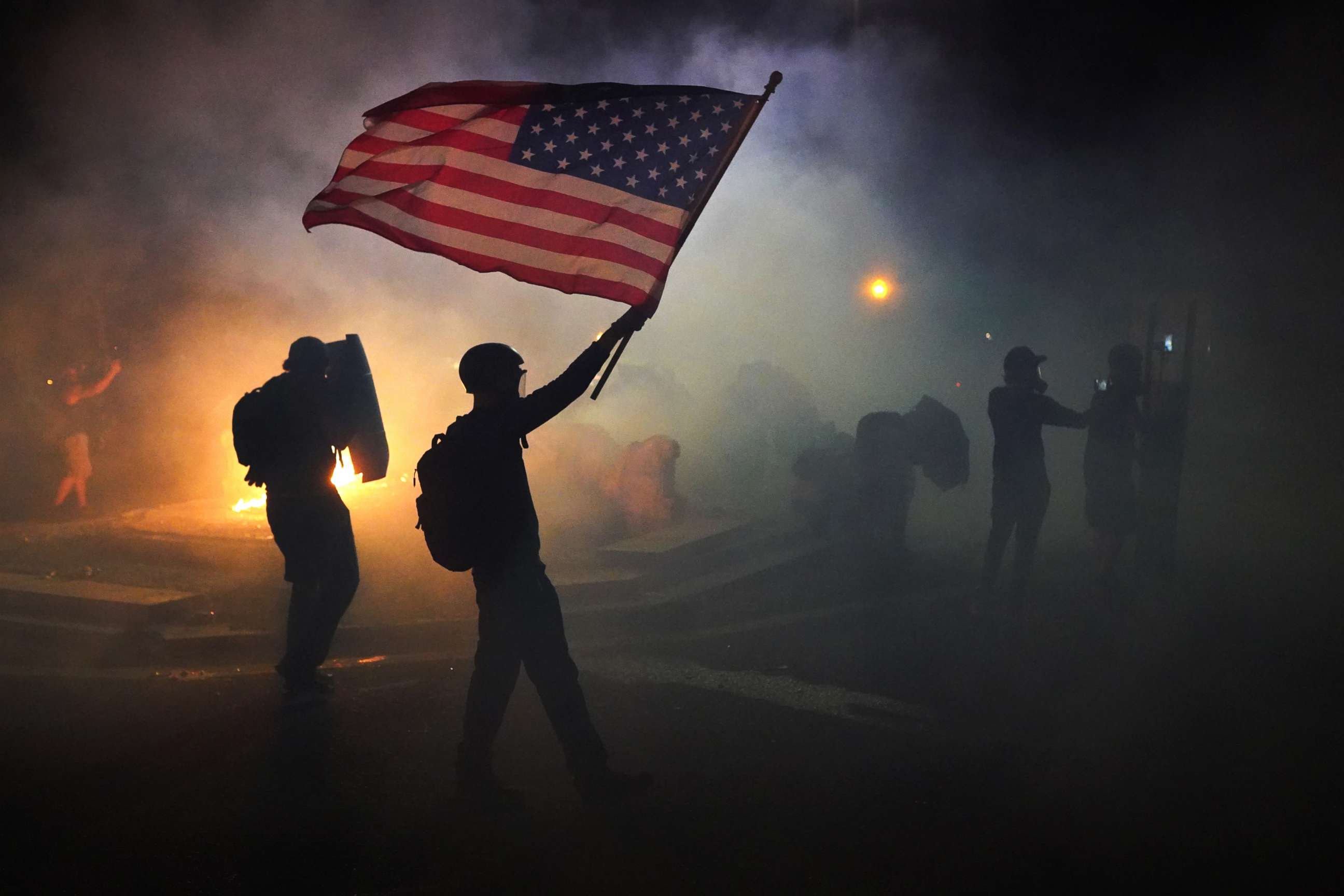 PHOTO: A protester flies an American flag while walking through tear gas fired by federal officers during a protest in front of the Mark O. Hatfield U.S. Courthouse on July 21, 2020 in Portland, Ore.