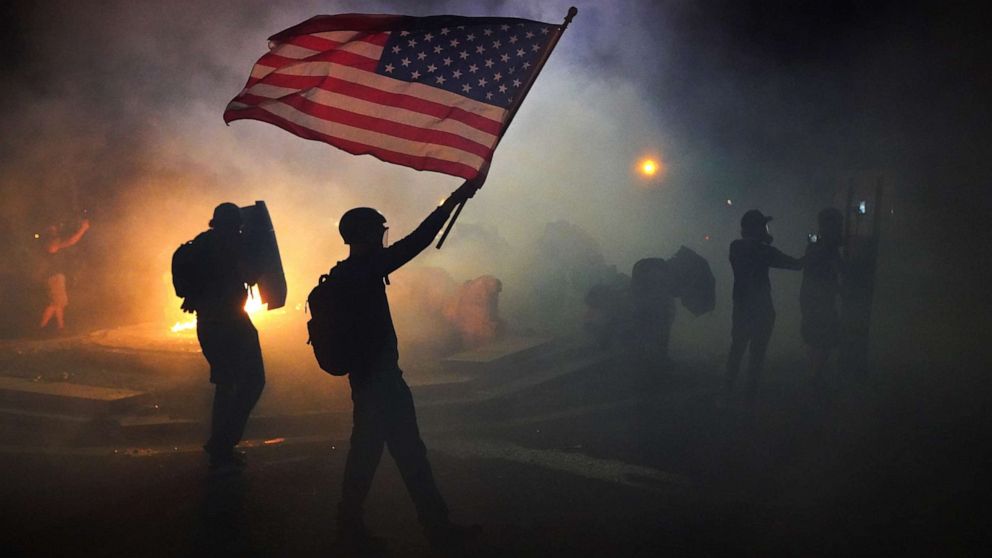 PHOTO: A protester flies an American flag while walking through tear gas fired by federal officers during a protest in front of the Mark O. Hatfield U.S. Courthouse on July 21, 2020 in Portland, Ore.