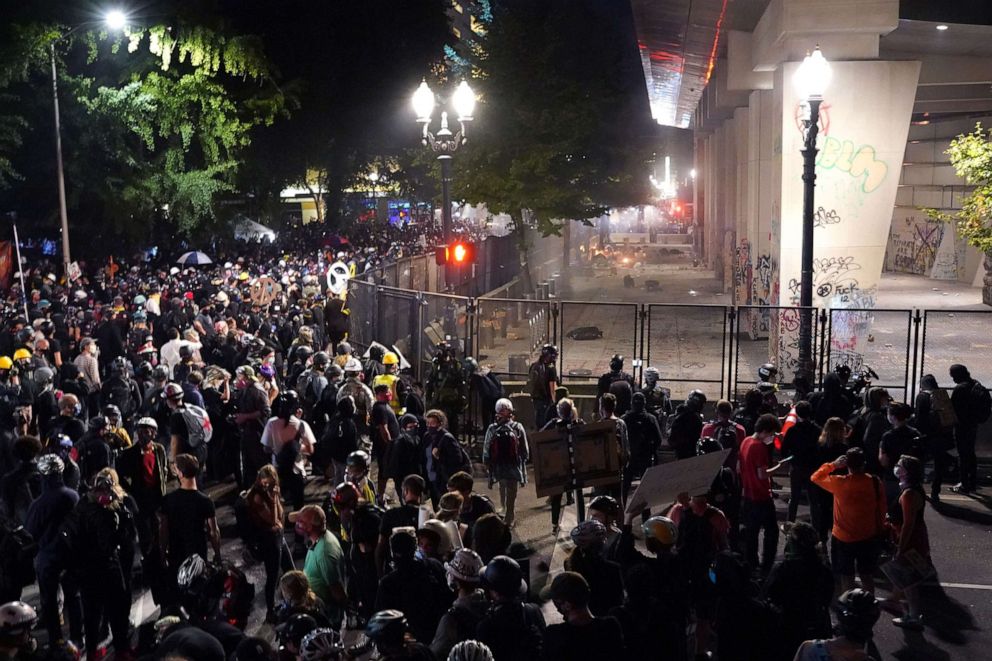 PHOTO: A crowd of protesters gather around a newly-reinforced permitter fence outside the Mark O. Hatfield U.S. Courthouse, July 22, 2020, in Portland, Ore.