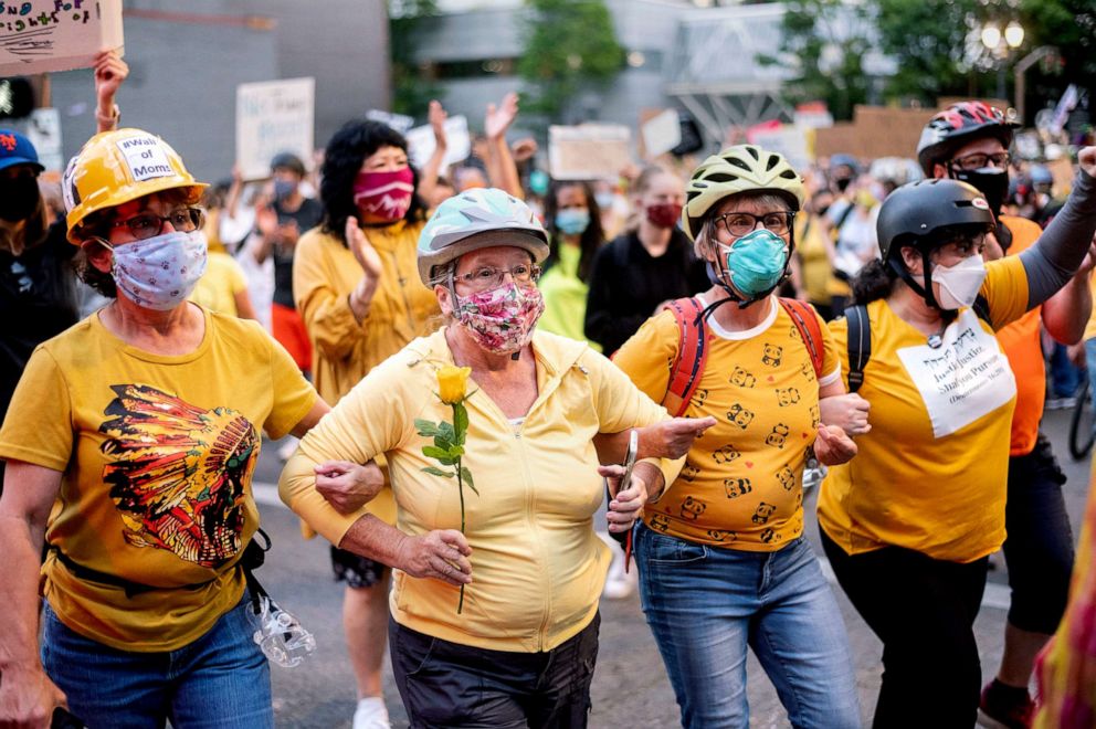PHOTO: Norma Lewis holds a flower while forming a "wall of moms" during a Black Lives Matter protest in Portland, Ore., on July 20, 2020.