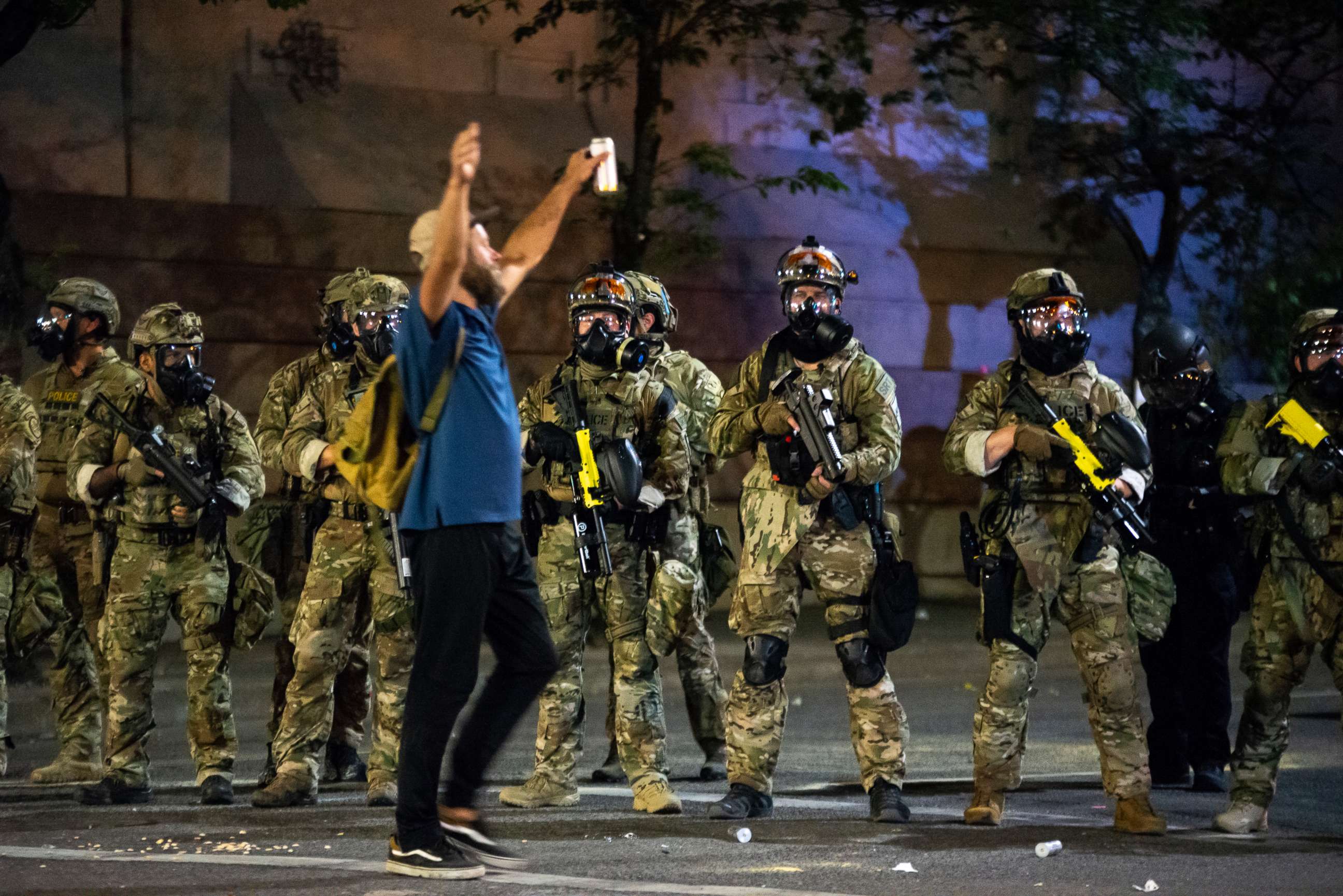 PHOTO: A protester holds his hands in the air while walking past a group of federal officers during a protest in front of the Mark O. Hatfield U.S. Courthouse on July 21, 2020, in Portland, Ore.